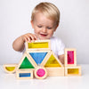 Enfant construisant une structure avec des blocs sensoriels Lumiblocks colorés en bois