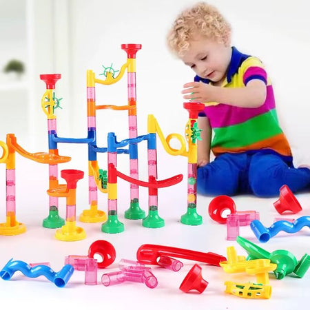 Enfant jouant avec un circuit à billes Billitrack en construisant un parcours coloré avec tubes et rampes
