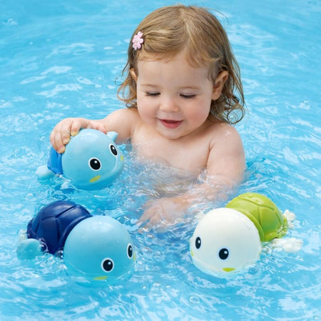 Bébé jouant dans l’eau avec des tortues nageuses colorées pour rendre le bain amusant et interactif