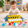 bébé assis sur tapis ouvrant un œuf Montessori et découvrant une forme colorée