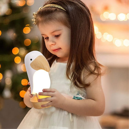Enfant tenant la veilleuse toucan LumaTouco portable dans une ambiance douce et rassurante