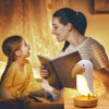 Parent lisant une histoire à son enfant avec la veilleuse toucan LumaTouco créant une ambiance chaleureuse